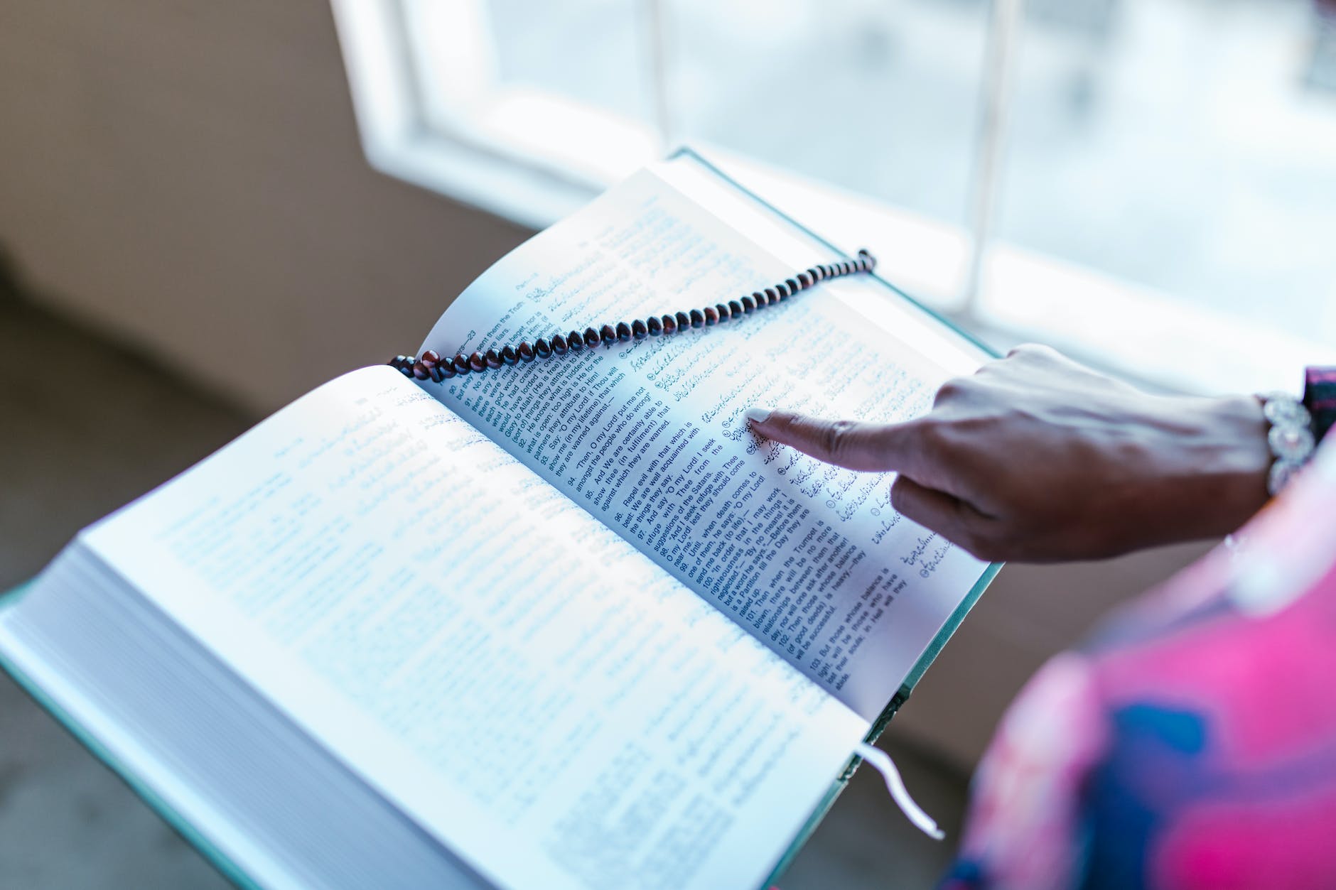 person pointing to an open book